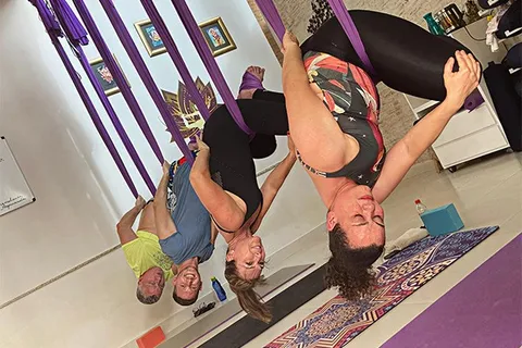 Fê Tavares e alunas em prática de yoga aéreo